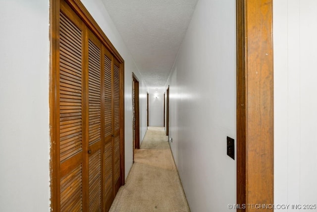 corridor featuring light colored carpet and a textured ceiling