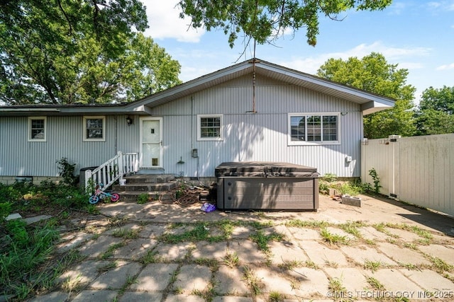 rear view of house with a hot tub and a patio