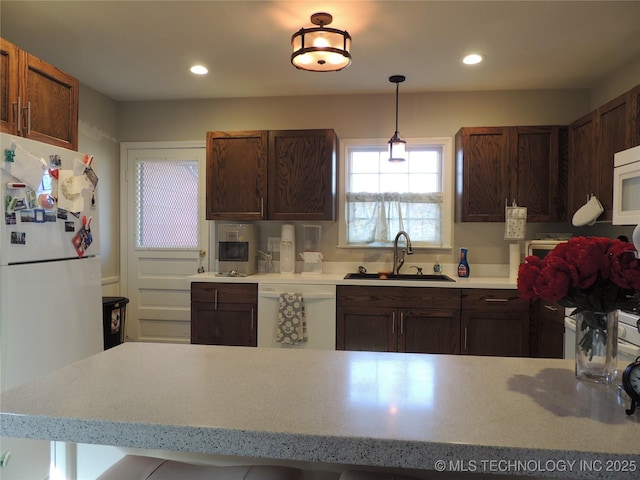 kitchen with sink, white appliances, and decorative light fixtures