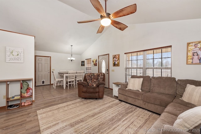 living room with wood-type flooring, ceiling fan with notable chandelier, and high vaulted ceiling