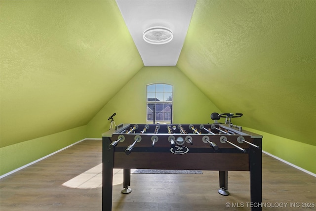 rec room featuring wood-type flooring, vaulted ceiling, and a textured ceiling