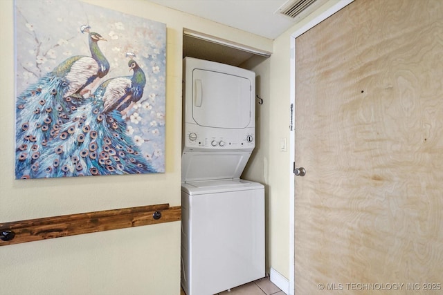 laundry area featuring stacked washing maching and dryer and light tile patterned floors