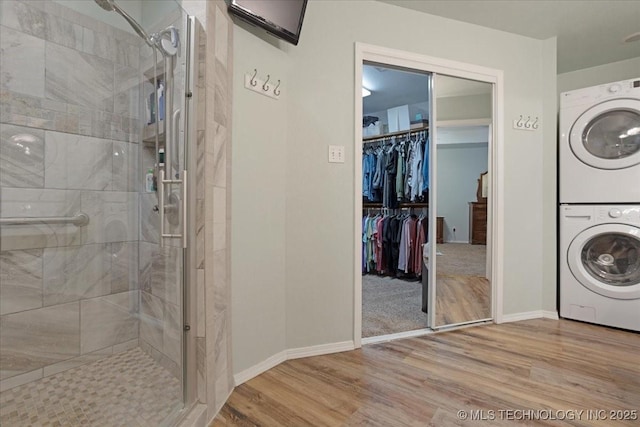 laundry area with stacked washing maching and dryer and light hardwood / wood-style flooring