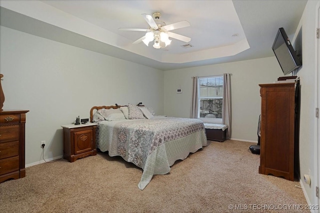 carpeted bedroom featuring a raised ceiling and ceiling fan