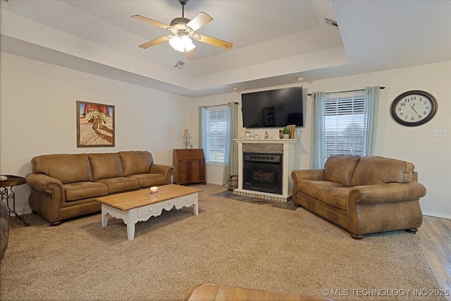 living room with a wealth of natural light, ceiling fan, and a tray ceiling