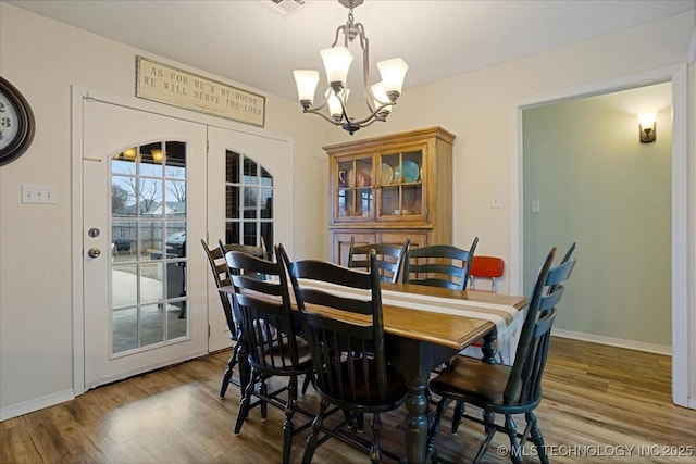 dining area with french doors, hardwood / wood-style floors, and a notable chandelier