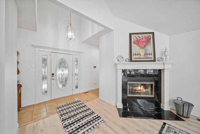 entryway with a tile fireplace, lofted ceiling, and hardwood / wood-style floors