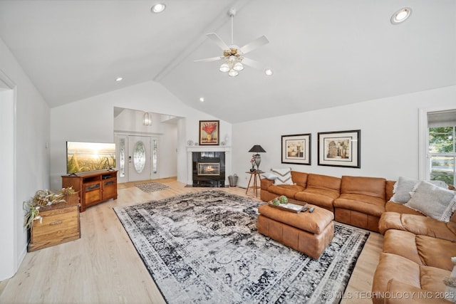 living room with a tiled fireplace, ceiling fan, lofted ceiling, and light hardwood / wood-style floors