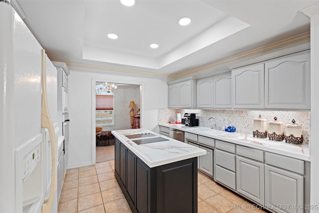 kitchen with sink, stainless steel appliances, a center island, a tray ceiling, and decorative backsplash