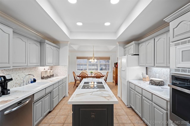 kitchen featuring appliances with stainless steel finishes, a tray ceiling, gray cabinets, and sink