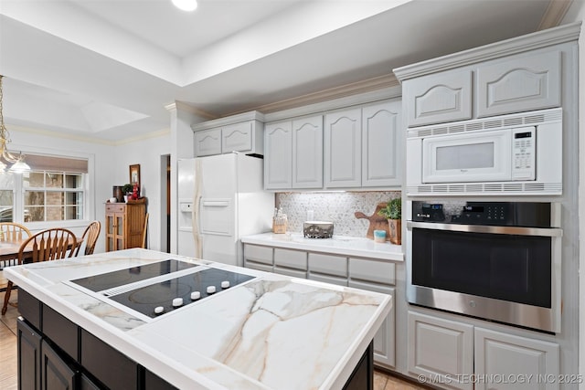 kitchen featuring tasteful backsplash, hanging light fixtures, a tray ceiling, crown molding, and white appliances