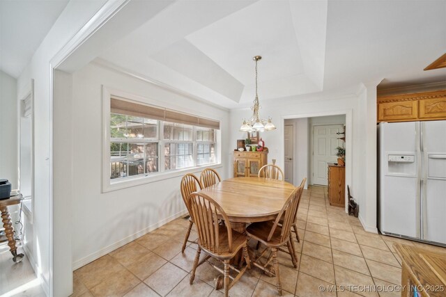 tiled dining space with a raised ceiling and a notable chandelier