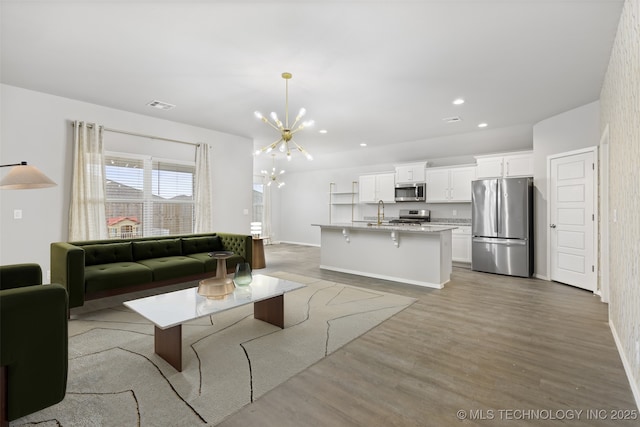 living room with an inviting chandelier, sink, and light wood-type flooring