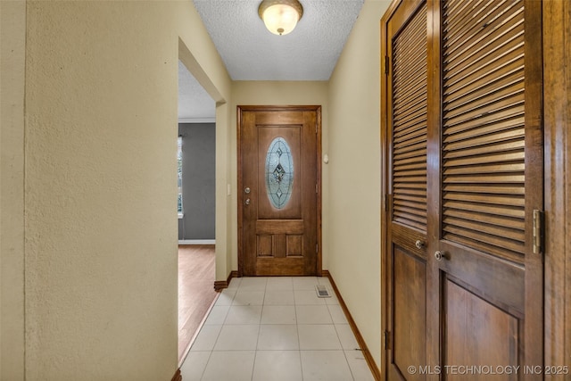 entryway featuring light tile patterned floors and a textured ceiling