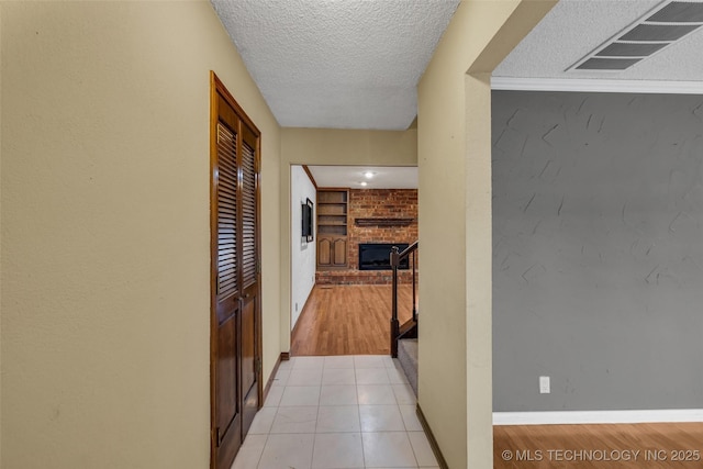 hallway with light tile patterned floors, built in features, and a textured ceiling