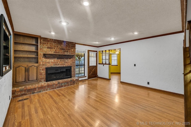 unfurnished living room with crown molding, a textured ceiling, light hardwood / wood-style flooring, built in features, and a fireplace