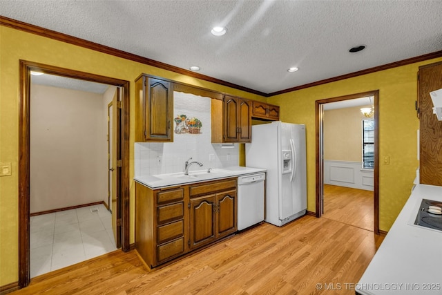 kitchen featuring sink, white appliances, ornamental molding, and light hardwood / wood-style floors