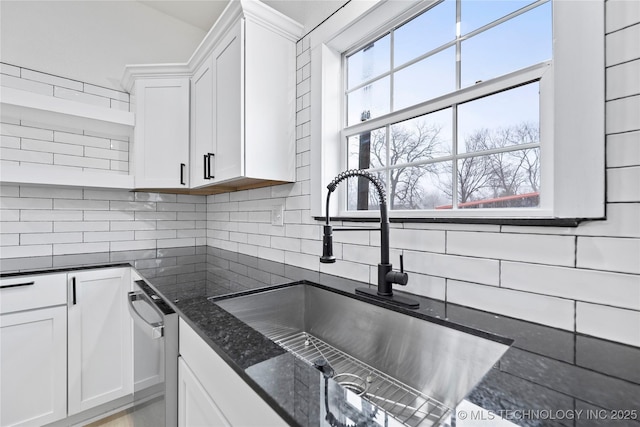 kitchen with white cabinetry, sink, backsplash, and dark stone counters