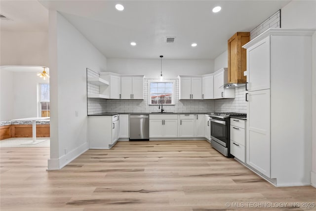 kitchen featuring sink, white cabinetry, hanging light fixtures, light hardwood / wood-style flooring, and appliances with stainless steel finishes