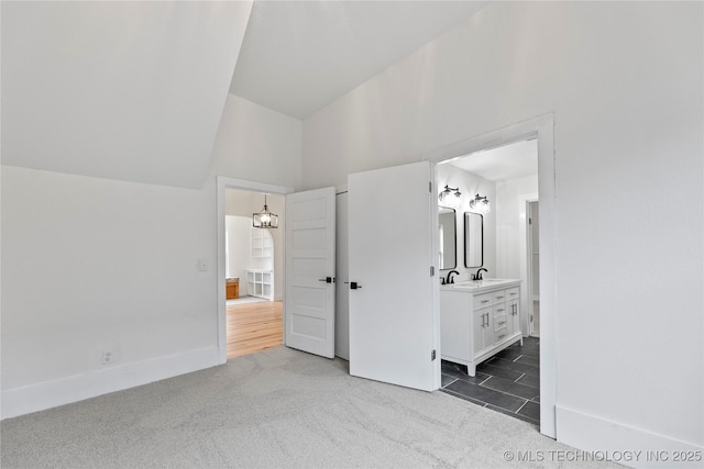 unfurnished bedroom featuring connected bathroom, dark carpet, vaulted ceiling, and sink