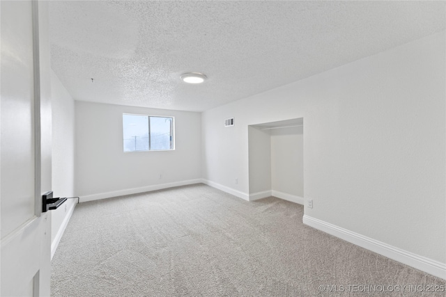 unfurnished room with carpet floors and a textured ceiling