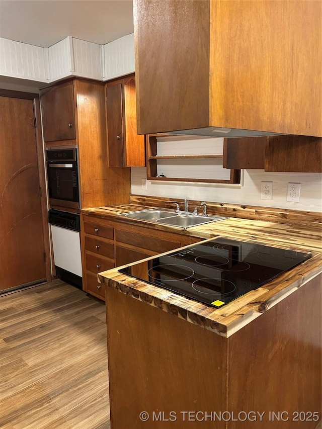 503 Parkview Dr, Bartlesville, OK 74003 - kitchen featuring oven, black electric stovetop, a sink, brown cabinetry, and wood finished floors