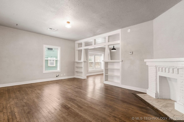 unfurnished living room with hardwood / wood-style flooring, a fireplace, a textured ceiling, and built in shelves