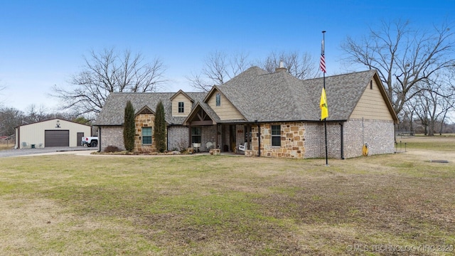 view of front of home with a garage, an outdoor structure, and a front lawn