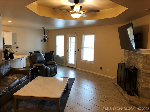 living room featuring a fireplace and ceiling fan with notable chandelier