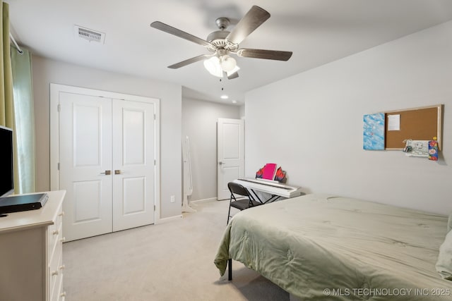 bedroom with a closet, light colored carpet, visible vents, ceiling fan, and baseboards