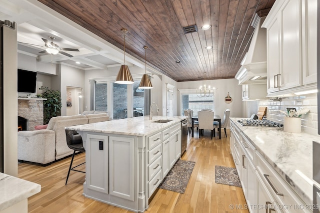 kitchen featuring an island with sink, white cabinetry, open floor plan, and hanging light fixtures