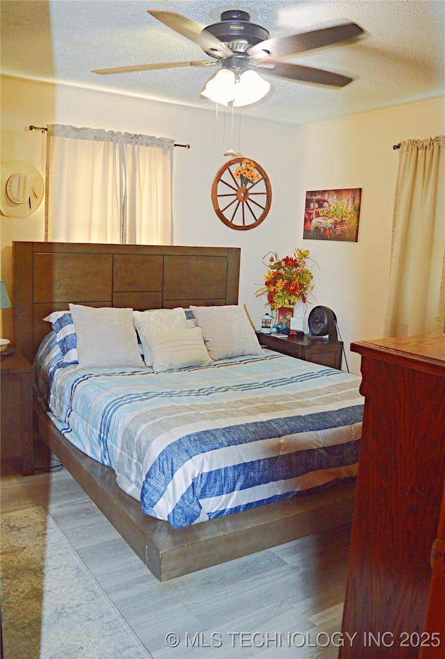 bedroom with ceiling fan and a textured ceiling