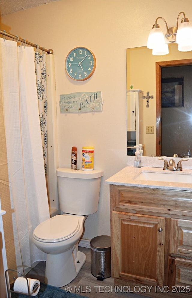 bathroom with walk in shower, vanity, and toilet