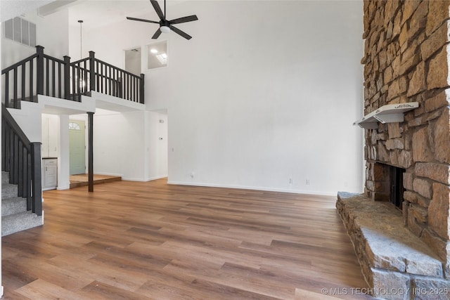 unfurnished living room featuring ceiling fan, wood-type flooring, and a fireplace