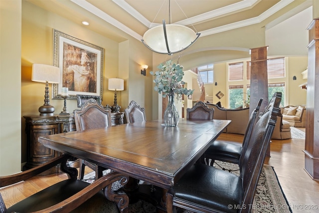 dining room with ornamental molding, a raised ceiling, and light wood-type flooring