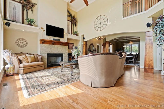 living room with crown molding, light hardwood / wood-style floors, a chandelier, and a towering ceiling