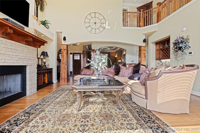 living room featuring a high ceiling, ornamental molding, a fireplace, and light wood-type flooring