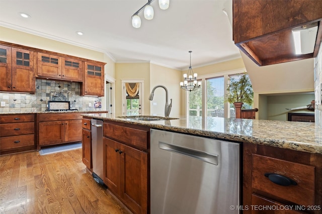 kitchen featuring sink, light stone counters, hanging light fixtures, stainless steel dishwasher, and decorative backsplash