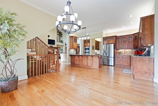 kitchen featuring tasteful backsplash, stainless steel appliances, hanging light fixtures, and light wood-type flooring