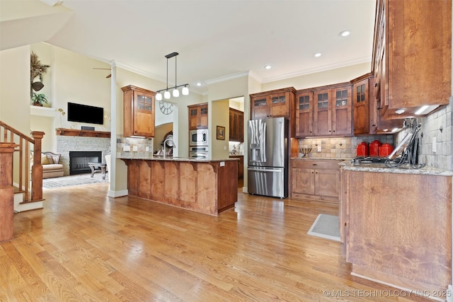 kitchen featuring pendant lighting, appliances with stainless steel finishes, light hardwood / wood-style floors, and light stone counters