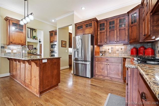 kitchen featuring crown molding, light stone counters, appliances with stainless steel finishes, pendant lighting, and light hardwood / wood-style floors