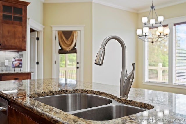 kitchen featuring sink, a wealth of natural light, a notable chandelier, and dark stone counters