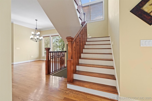 staircase with an inviting chandelier, crown molding, and wood-type flooring