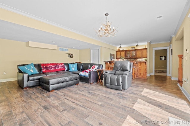 living room featuring wood-type flooring, ornamental molding, and a chandelier