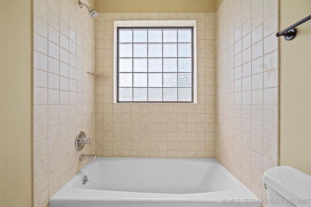 bathroom with tiled shower / bath combo and toilet