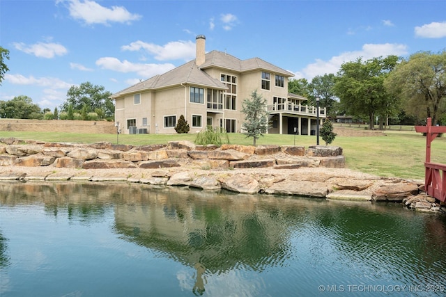 rear view of property with a deck with water view and a yard