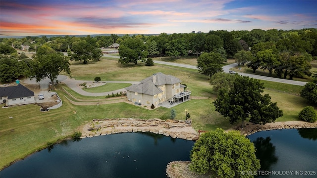 aerial view at dusk featuring a water view