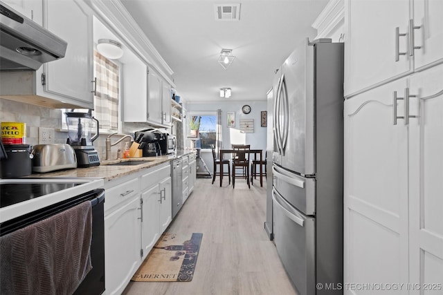 kitchen featuring sink, light hardwood / wood-style flooring, stainless steel fridge, backsplash, and white cabinets