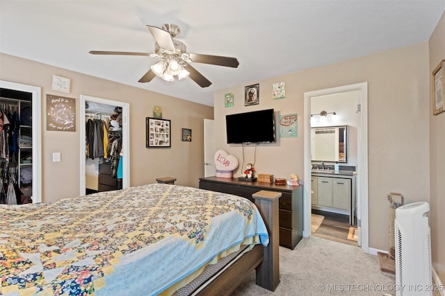 carpeted bedroom with connected bathroom, sink, and ceiling fan