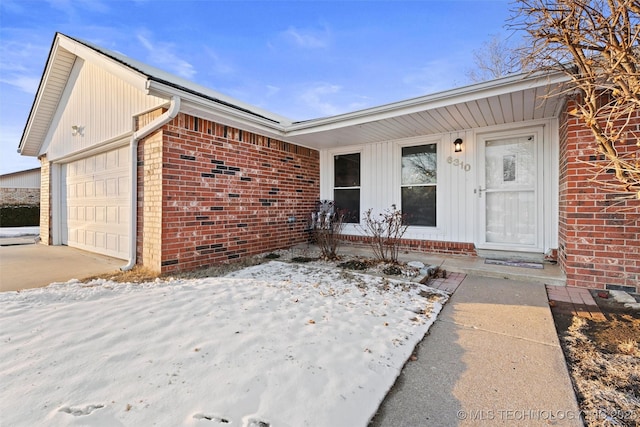 snow covered property entrance with a garage